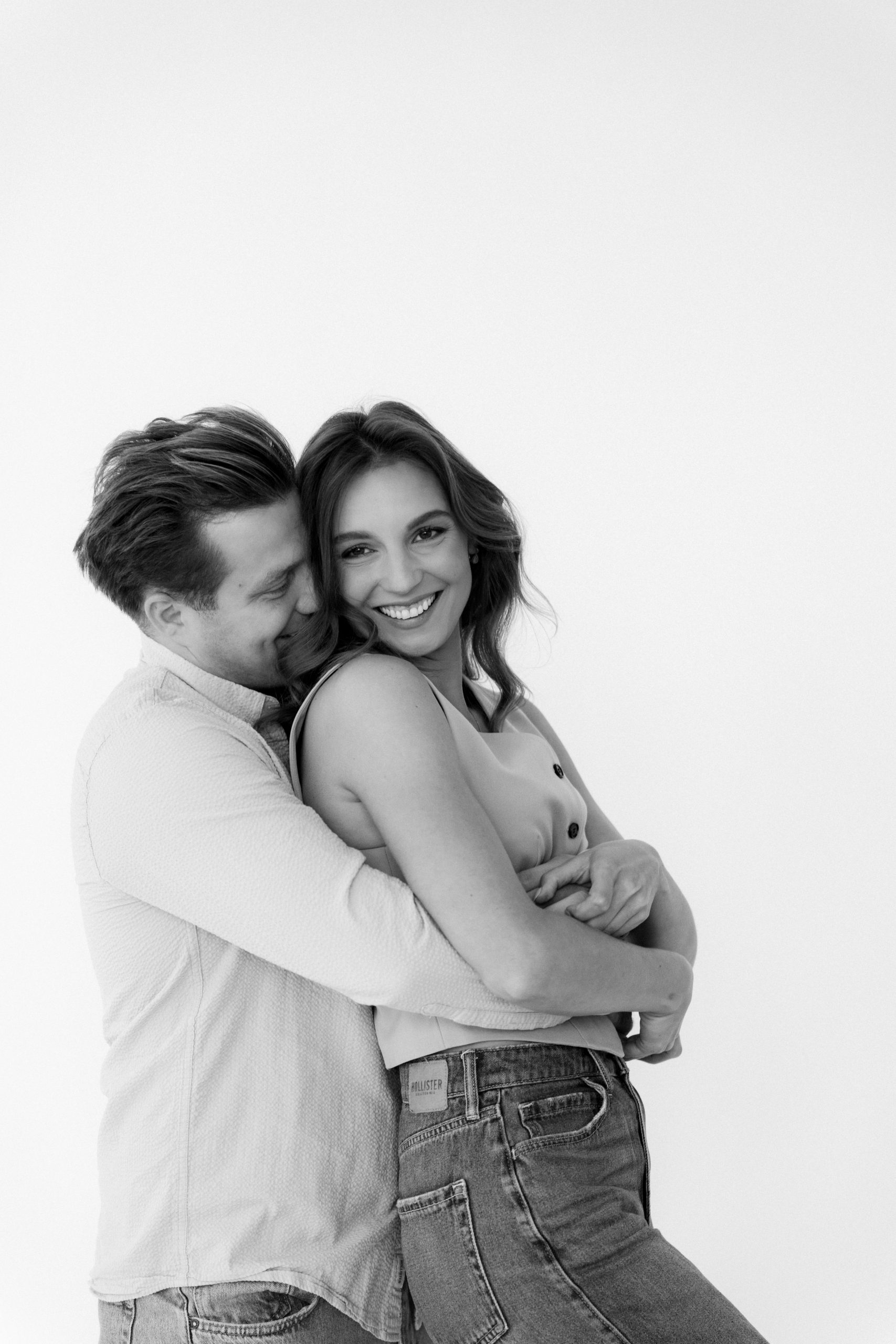 Černobílý párový portrét plný radosti a lásky. Zamilovaná dvojice v objetí, foceno v HLight Studiu fotografem Lukášem Vavřincem.