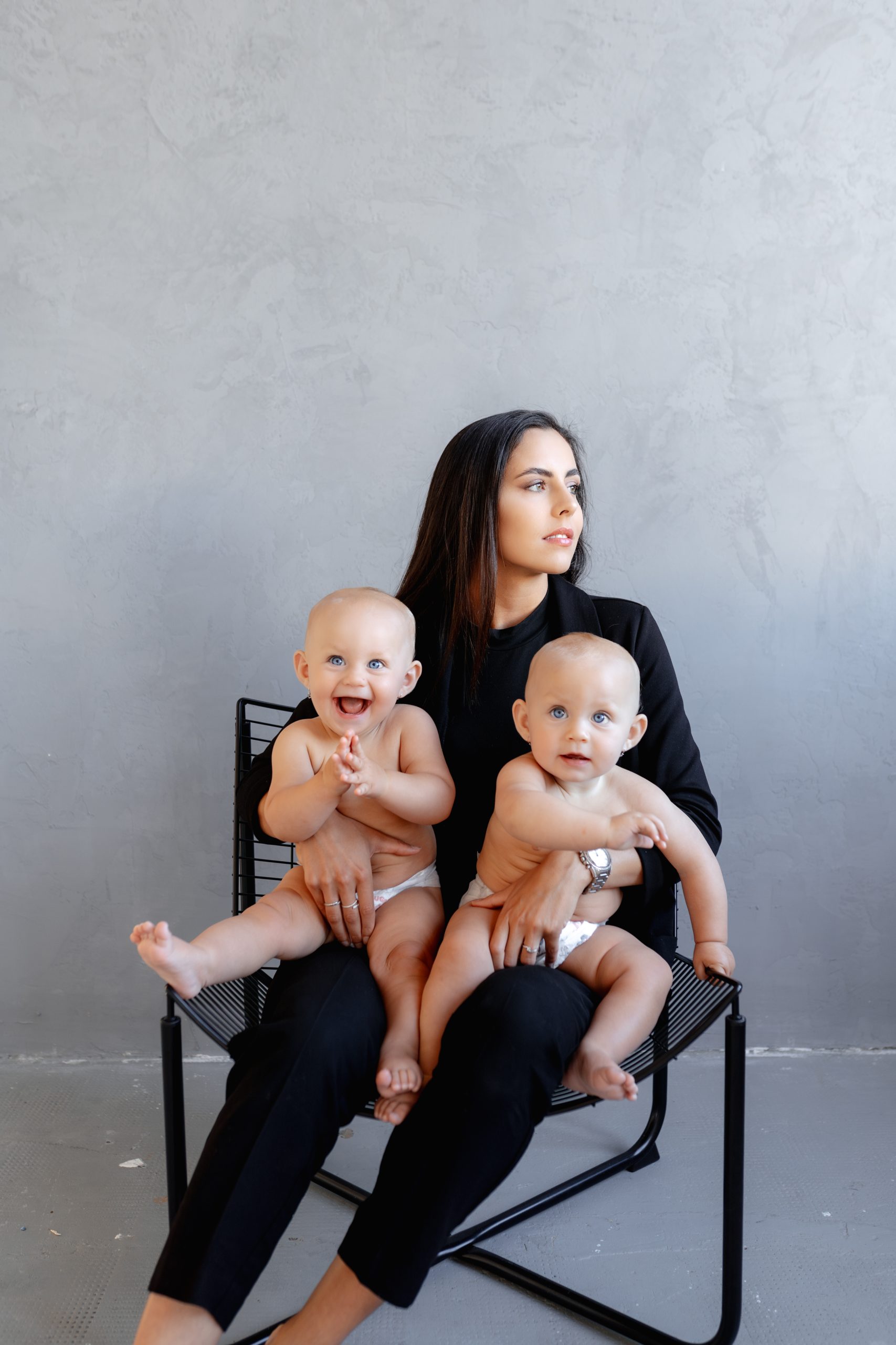 Rodinné focení dvojčat v ateliéru HLight Studio – fotograf Lukáš Vavřinec zachytil maminku s dvěma malými dětmi na moderní židli.
