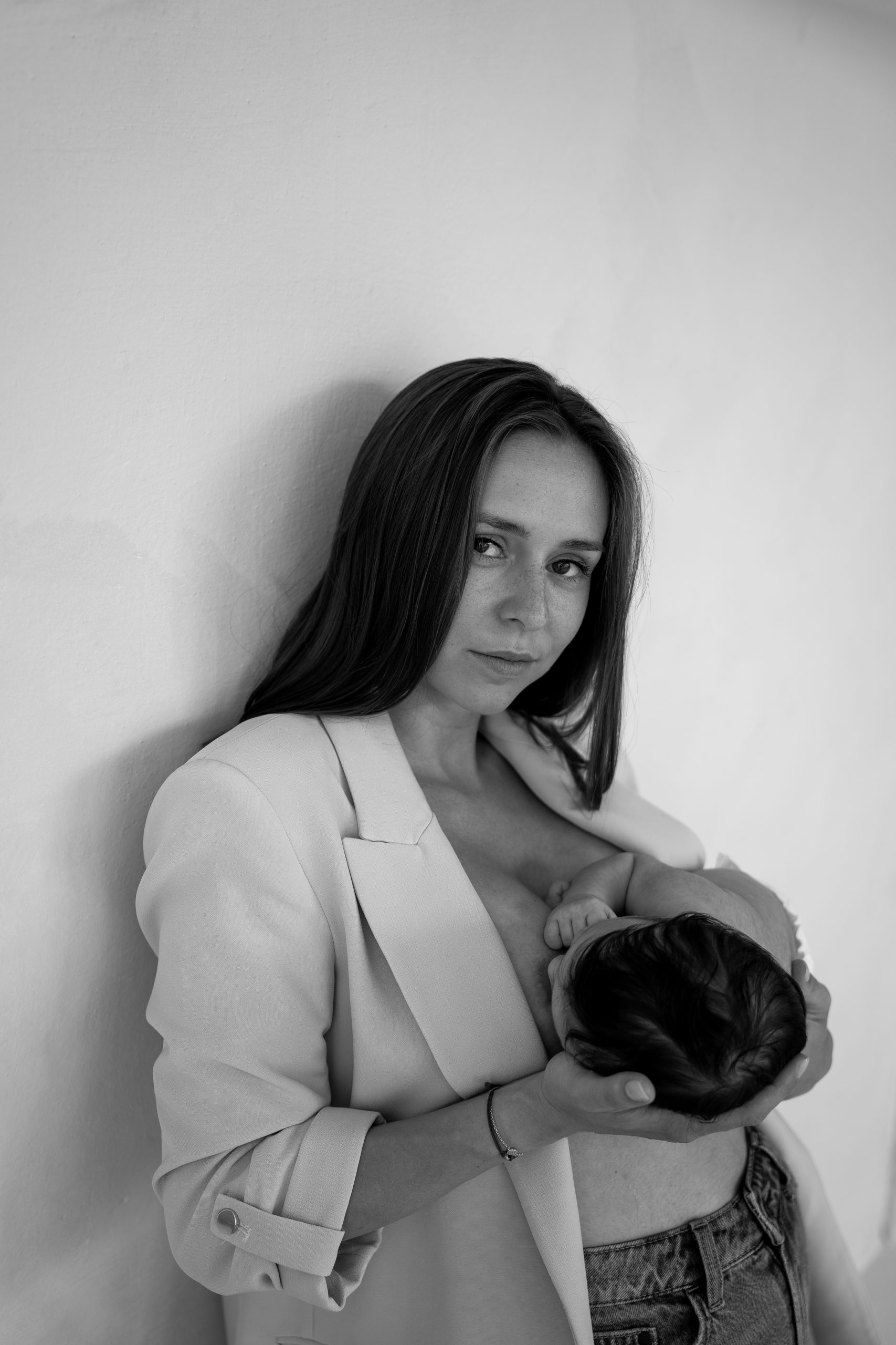 Černobílá portrétní fotografie maminky kojící své miminko. Pořízeno v HLight Studio fotografem Lukášem Vavřincem, s důrazem na intimitu a přirozené emoce.